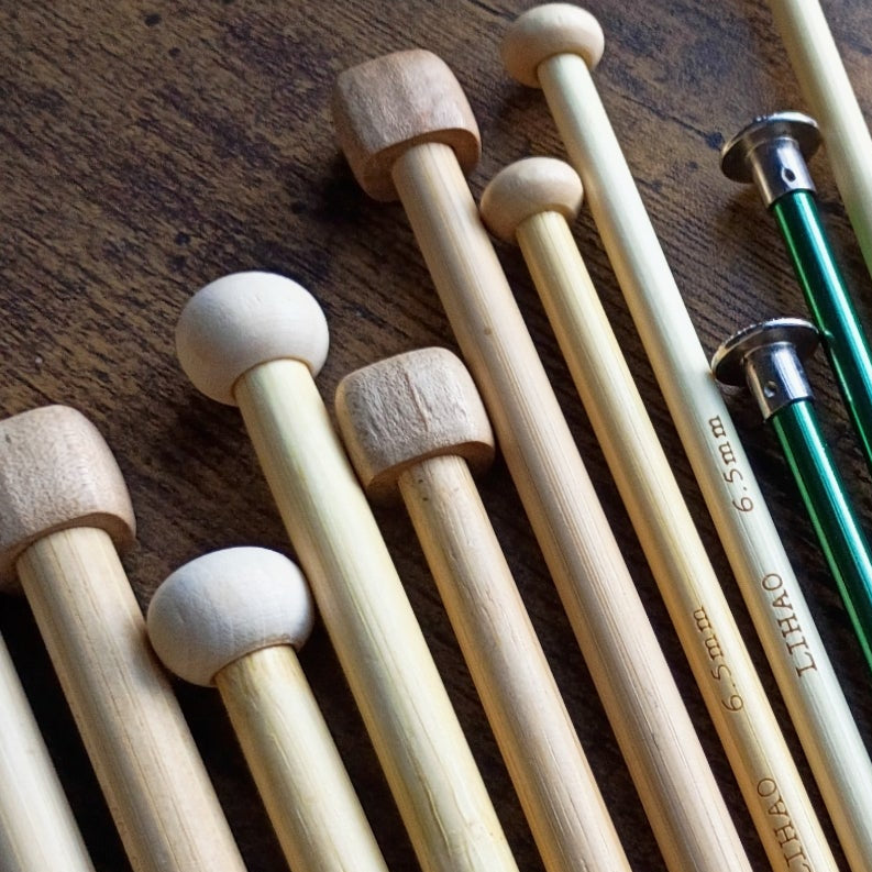 Set of knitting needles on a wooden surface