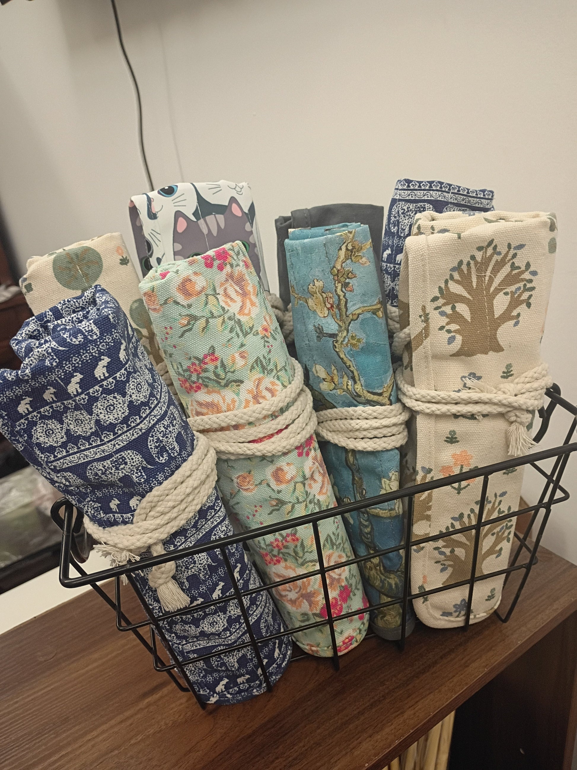 Canvas roller storage bags in various patterns displayed in a wire basket